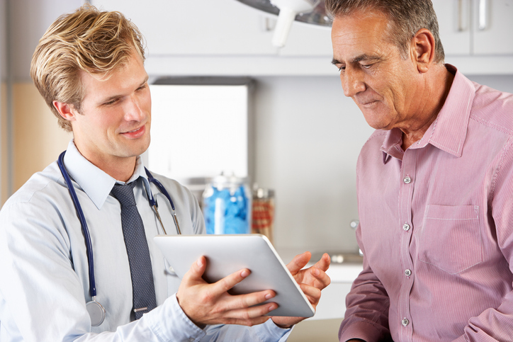 Male Doctor Discussing Records With Senior Patient Using Digital Tablet, discussing Peyronie’s Disease .