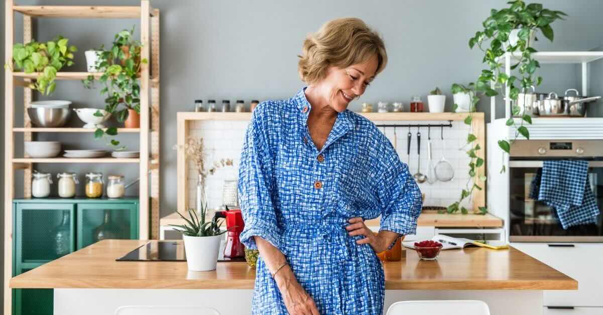 Middle age woman in bright kitchen, smiling, looking away