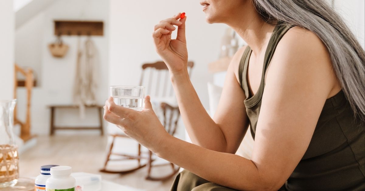Middle age woman taking hormone pills in living room