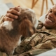 Lifestyle photo of man laughing and petting dog while lying on couch