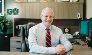 Dr. Andrew Kirsch sitting at desk with arms crossed on desktop, smiling