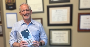 Dr. Andrew Kirsch holding his new book, The Ultimate Bedwetting Survival Guide
