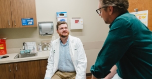 Dr. Kemper sitting on chair while meeting with patient sitting on examination table