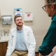 Dr. Kemper sitting on chair while meeting with patient sitting on examination table