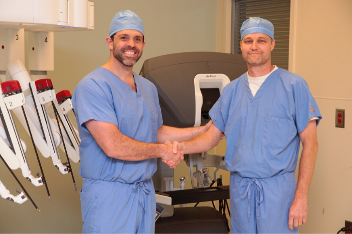 Photo of Dr. Sharpe and Dr.Gonzalez shaking hands in front of surgery equipment.