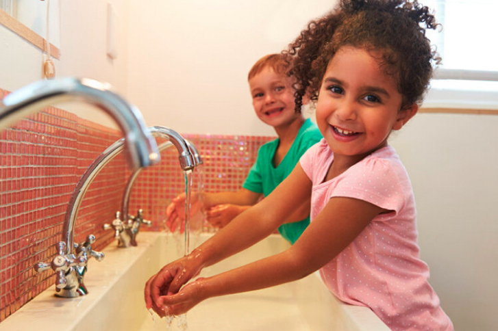 Two children washing their hands appropriately, figuring out how to work against urinary incontinence at school.