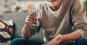 Man taking a blue pill with water