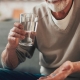 Man taking a blue pill with water