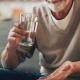Man holding pill, sipping water