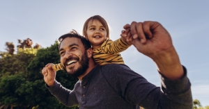 Dad walking with child on back while holding child's hands