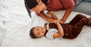 Mother laughing with toddler son while lying together
