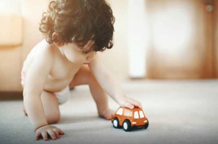 Male toddle who is playing with a toy car.