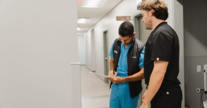 Doctor writing on paper with another doctor looking over