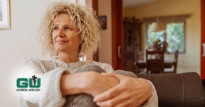 Woman sitting with knees to chest holding knees with both hands and looking to the side