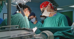 Georgia Urology doctors in green surgical scrubs performing a medical procedure in a clinical setting.