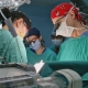 Georgia Urology doctors in green surgical scrubs performing a medical procedure in a clinical setting.