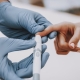 Doctor in blue gloves uses lancing device on diabetic patient