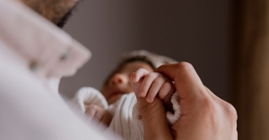 Father holding baby with Spina Bifida, focus on baby holding fathers finger