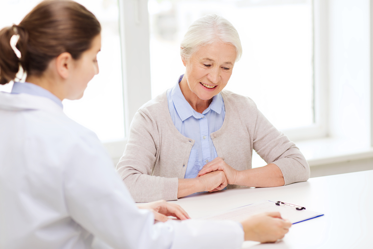 doctor with clipboard and senior woman at hospital, discussing urinary tract fistula.