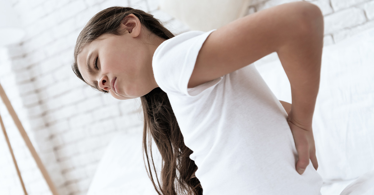 Child holding back in pain from kidney stone.