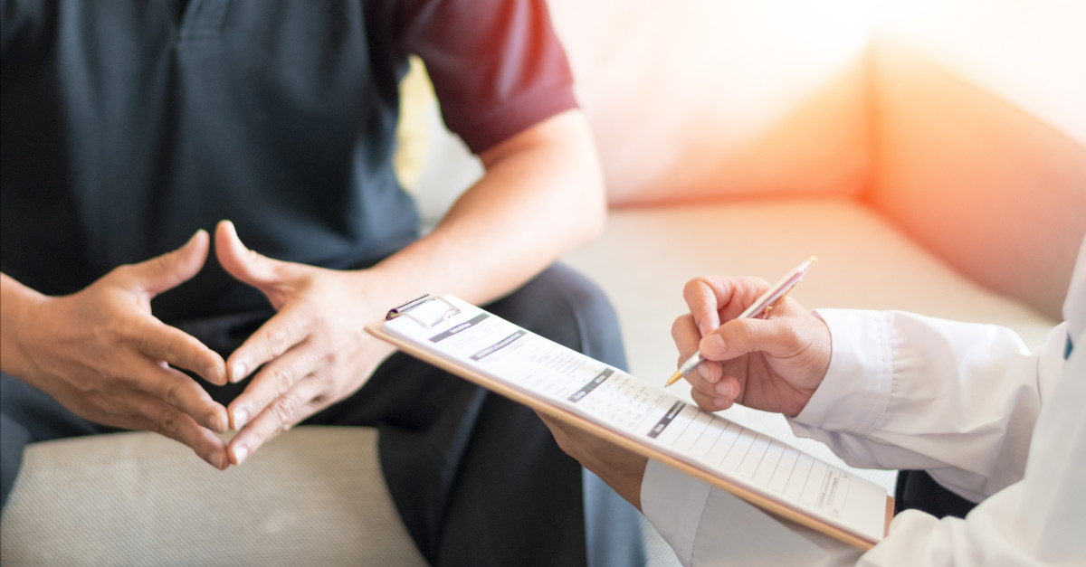 Doctor holding clipboard speaking to client about erectile dysfunction