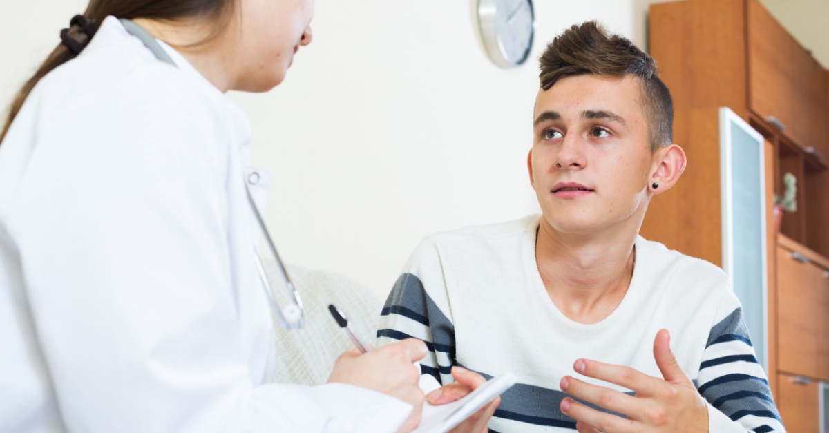 Physician consulting a teenage boy in a medical office
