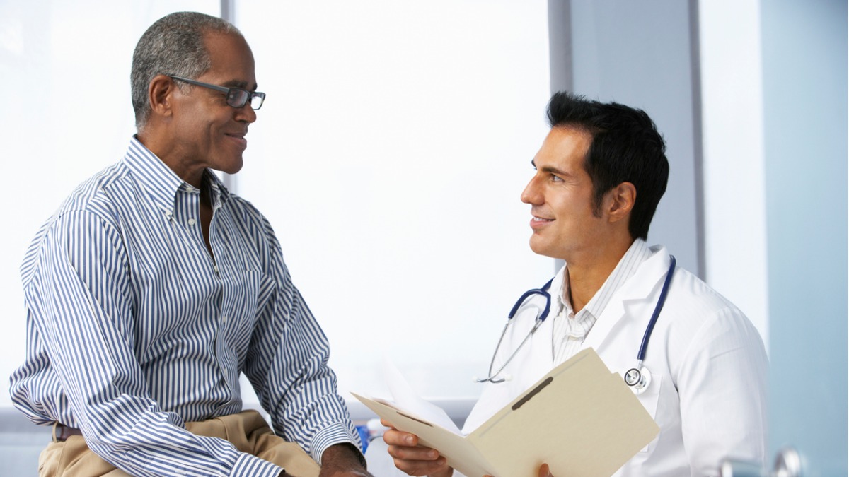 An African American man speaking to a urologist, asking the five questions men should ask about prostate cancer.