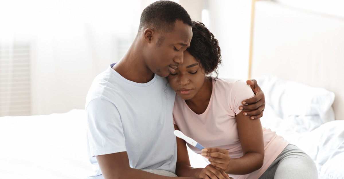 Man and woman hugging while holding pregnancy test