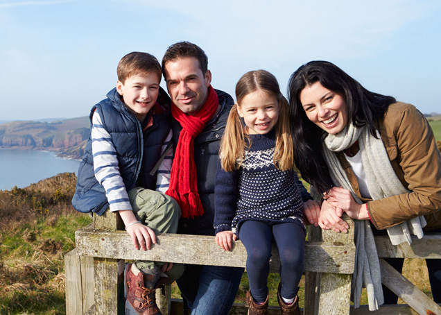 Happy family of four smiling at the camera, wondering if a vasectomy can be reversed.