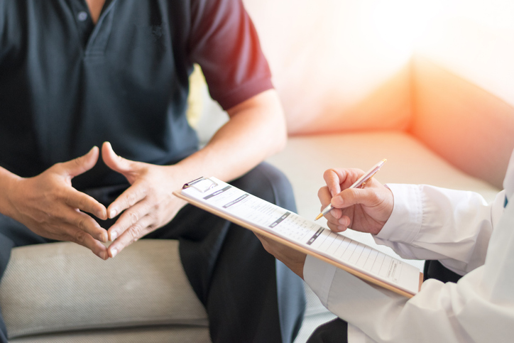 Man sitting on a coach speaking with a doctor.