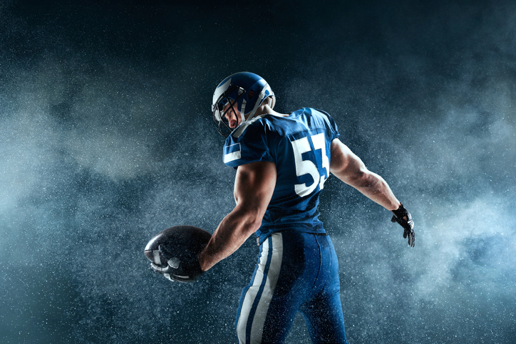 American football, football player standing in dramatic lighting.