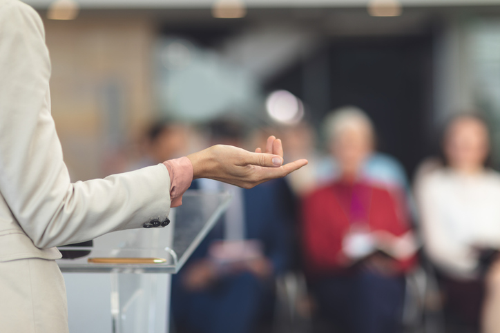 Mid section of mixed race female speaker speaking at a business seminar in modern office.