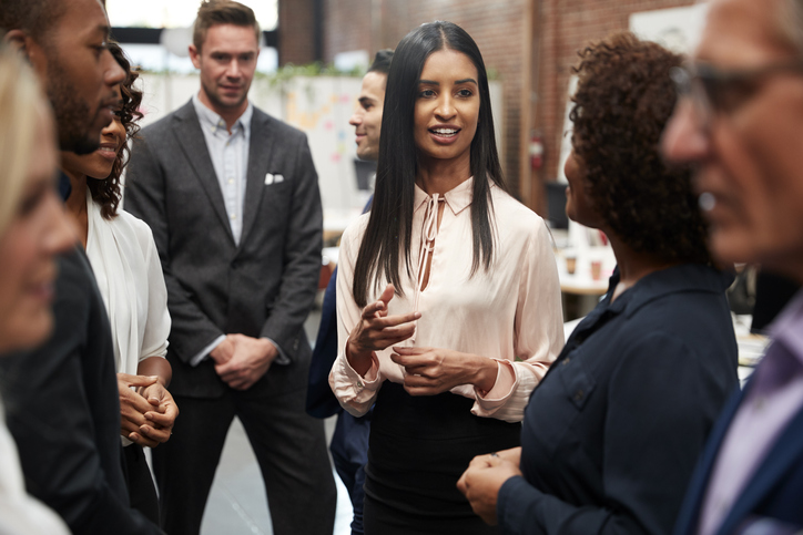 Business Team Standing Having Informal Meeting In Modern Office.