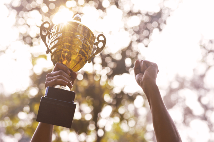 Holding gold trophy in nature background, Vintage style.