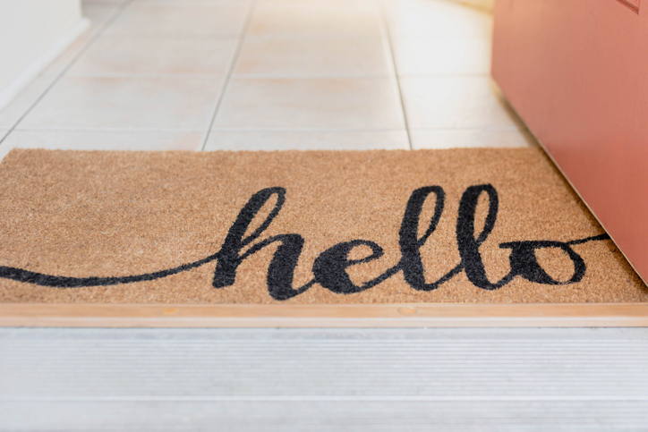 Cute rug with the word hello written in script at the entrance of a home welcoming guests