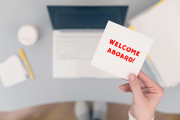 Woman clerk sitting holding note paper sticker with welcome aboard phrase. Business concept. Concept.