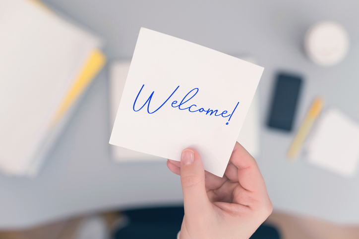 Woman clerk sitting holding note paper sticker with Welcome word. Business concept. Concept.