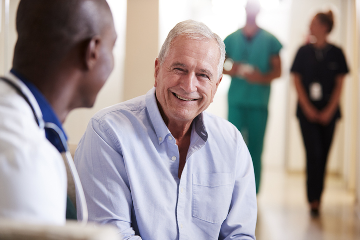 Doctor Welcoming To Senior Male Patient Being Admitted To Hospital, discussing Male Reconstructive Surgery