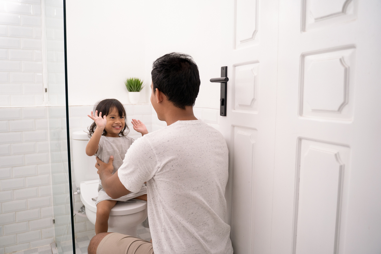 togetherness of father and his daughter high five in the bathroom, dealing with the poop on scoop.