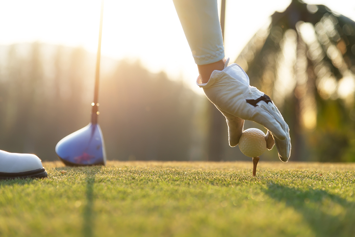 hand of woman golf player gentle put a golf ball onto wooden tee on the tee off, to make ready hit away from tee off to the fairway ahead. Healthy and Lifestyle Concept.