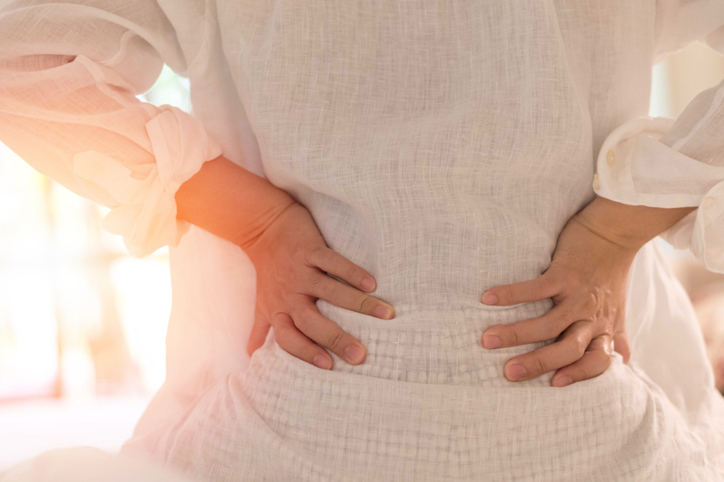 Back pain in woman concept. Female patient hurt from lower backache from bowel and bladder problems, palvic inflammatory disease (PID) or motherhood pregnancy or kidney stones.