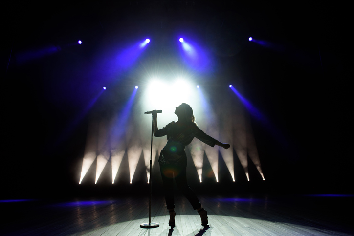 Silhouette of singer on stage. Dark background, smoke, spotlights.