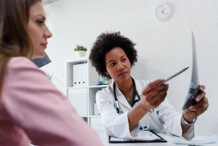 Doctor talking with patient at desk in medical office.