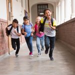 Cute pupils running down the hall at the elementary school, not worried about bedwetting.