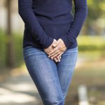 Woman with Hands Holding her Crotch, dealing with incontinence.