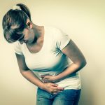 Woman with menstrual pain is holding her aching belly - isolated on white background, wondering why do bladders fall.