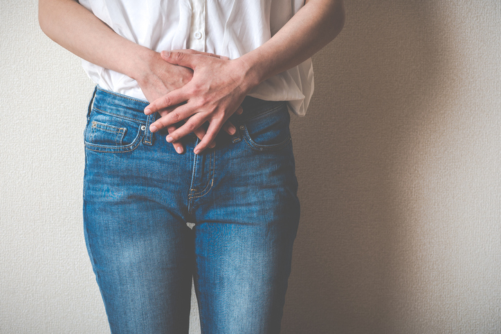 Women touching lower abdomen, wondering how to prevent UTIs.