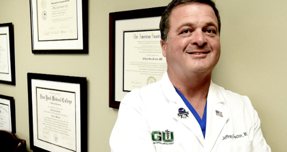 Urologist Dr. Jeffrey Proctor standing in front of his accolades in his office.