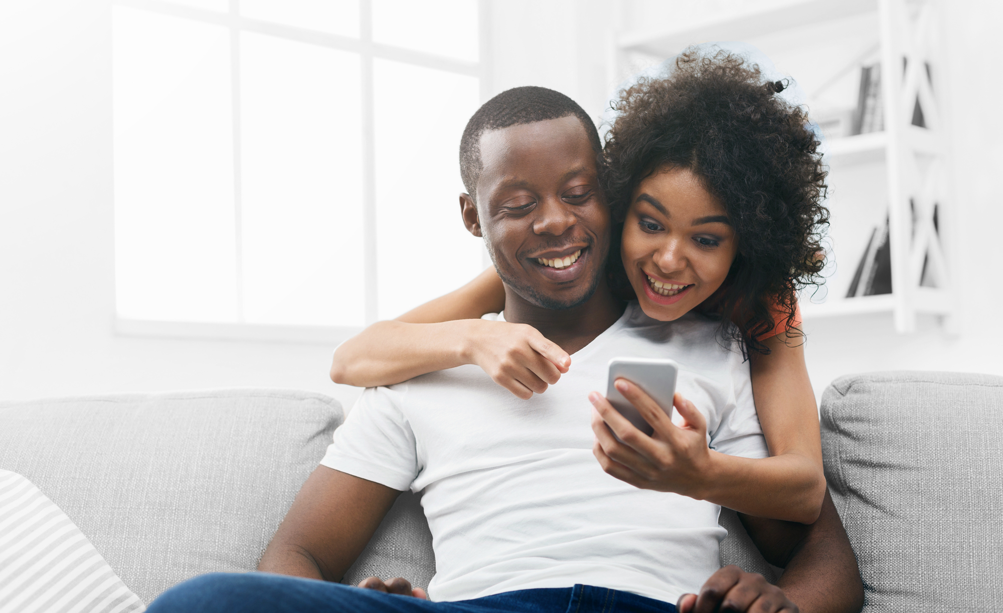 Young couple staring excitingly at a cell phone. | Georgia Urology