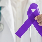 Doctor holding a purple ribbon for Testicular cancer Awareness Month